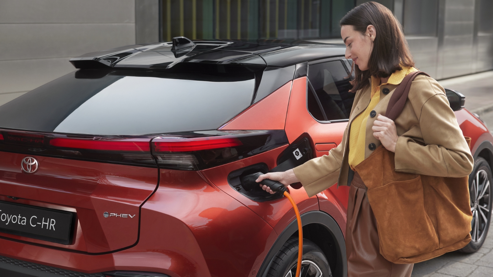 Kobieta ładuje Toyotę C-HR