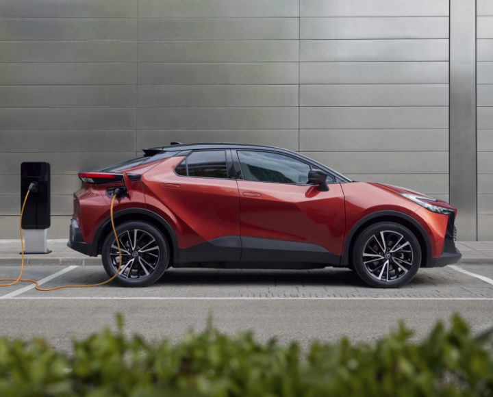 Pomarańczowa Toyota ładuje się na stacji ładowania